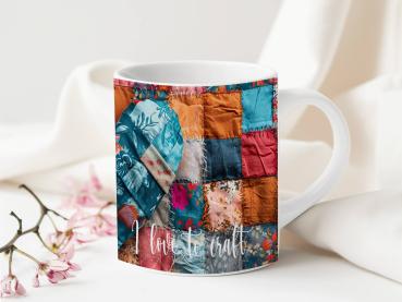Weißer Keramikbecher mit einem farbenfrohen Patchwork-Design, das ein Herzmotiv zeigt. Der Becher ist mit Stoffmustern in Blau-, Rot-, und Orangetönen bedruckt, und der Text 'love to craft' ist in einer weißen, geschwungenen Schrift am unteren Rand sichtb